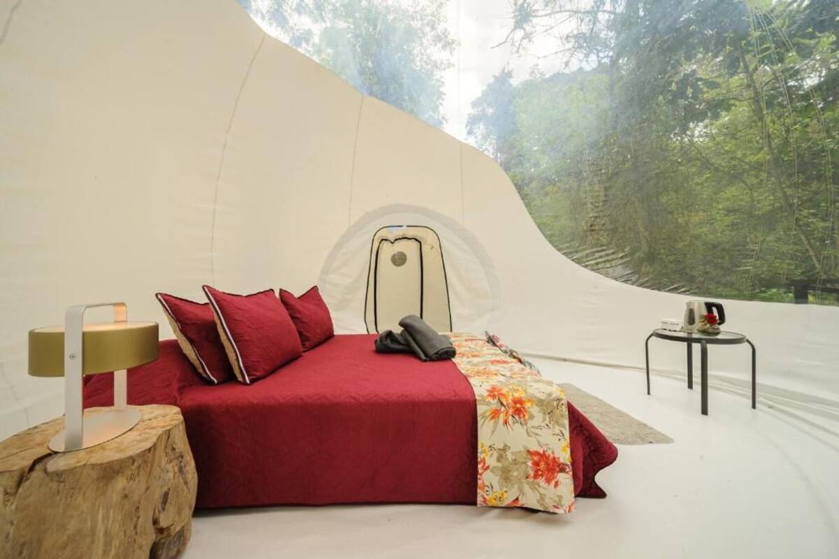Ein gemütliches Zelt-Schlafzimmer mit Bett, Kissen, einer Lampe und einem kleinen Tisch.