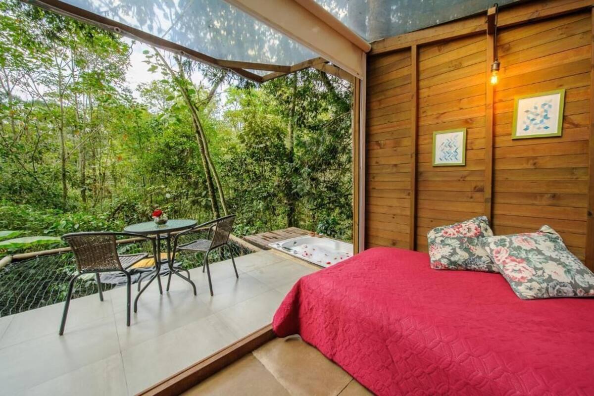 Ein Schlafzimmer mit einem großen Bett, einem Holzkopfende und Blick auf einen üppigen Garten.