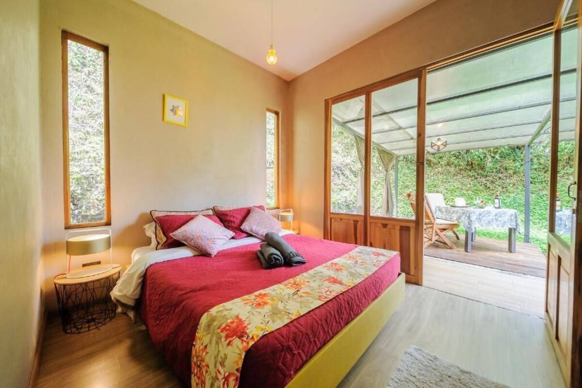 Ein Schlafzimmer mit einem großen Bett, einem Fenster und Blick ins Freie.