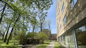 A courtyard with outdoor seating, a pathway, and a building with large windows. - Saint-paul Residence (Ottawa)