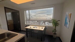 A small kitchen with a window, a table with chairs, a sink, and a potted plant. - Saint-paul Residence (Ottawa)