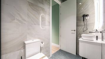 Deluxe appartement | Badkamer | Een douche, een haardroger, handdoeken, zeep