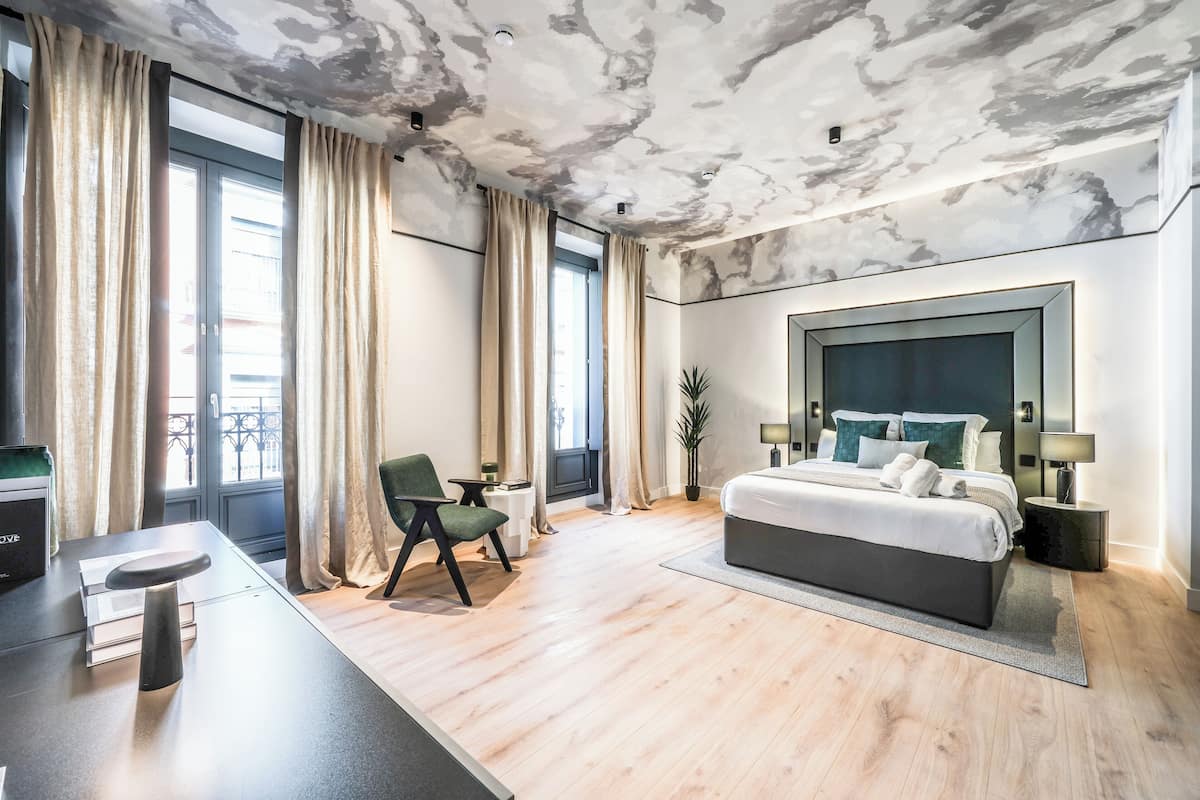 Een moderne slaapkamer met een groot bed, een bureau en een stoel.