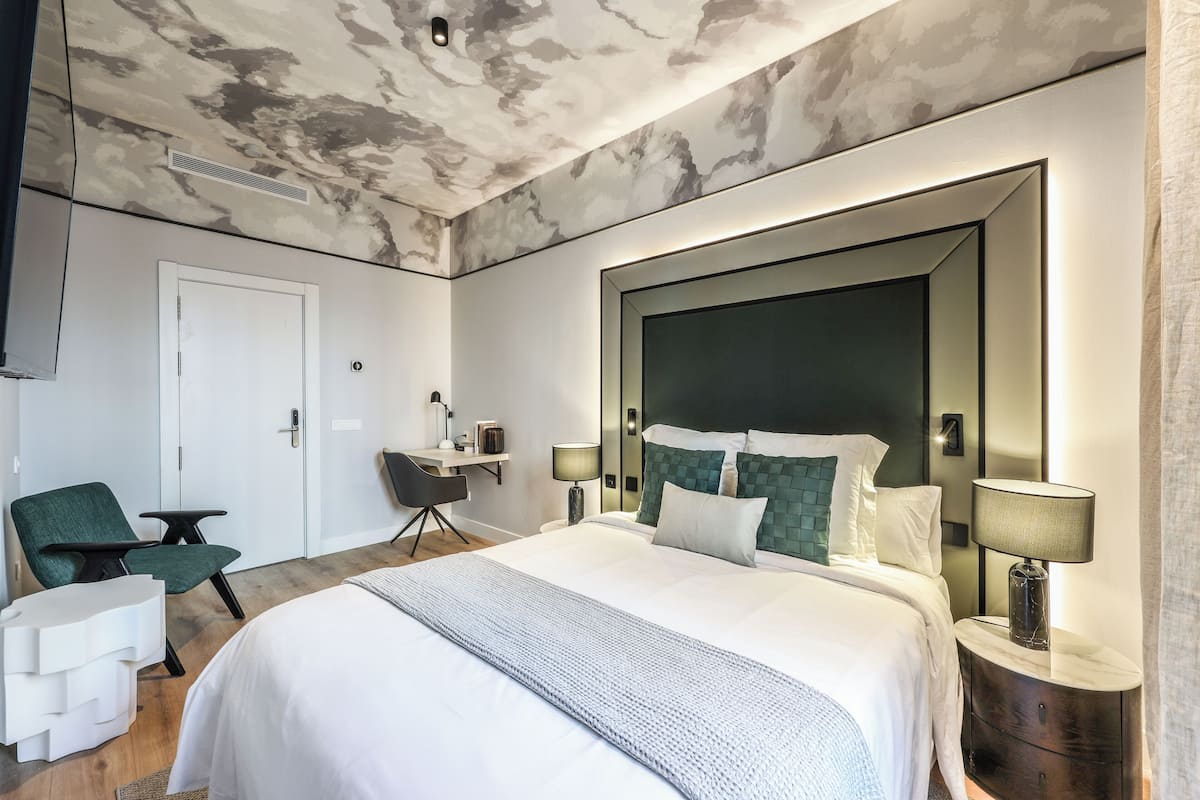 Een moderne hotelkamer met een groot bed, een bureau, een stoel en een grote spiegel.