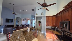 A spacious living area with a kitchen, a dining area, and a ceiling fan. - Closest Home to South Beach on Marco Island (Marco Island)