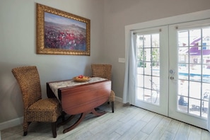 A dining area with a wooden table, wicker chairs, and a framed picture on the wall. - Tank House Stay for 2 in Comfort Texas Access to Pool Hot Tub (Comfort)