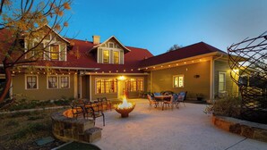 A two-story house with a fire pit in the center, surrounded by outdoor seating. - 1906 Haus Stay for 13 with Access to Pool  Hot Tub (Comfort)