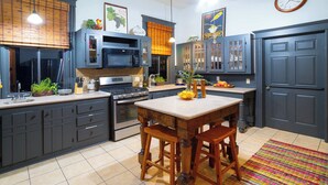 A kitchen with dark cabinets, a wooden island, and a colorful rug. - 1906 Haus Stay for 13 with Access to Pool  Hot Tub (Comfort)