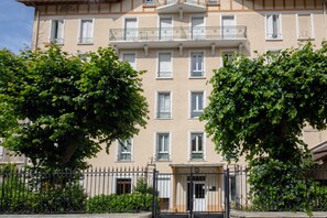A multi-story building with a symmetrical facade, balconies, and a gated entrance.