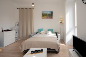 A bedroom with a bed, bedside table, TV, and a window with a view of mountains.