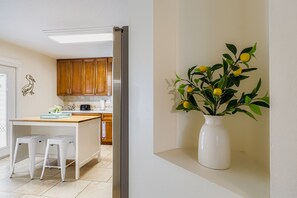 Eine moderne Küche mit Holzschränken, einer weißen Arbeitsplatte und einer Vase mit Zitronen auf einem Regal.