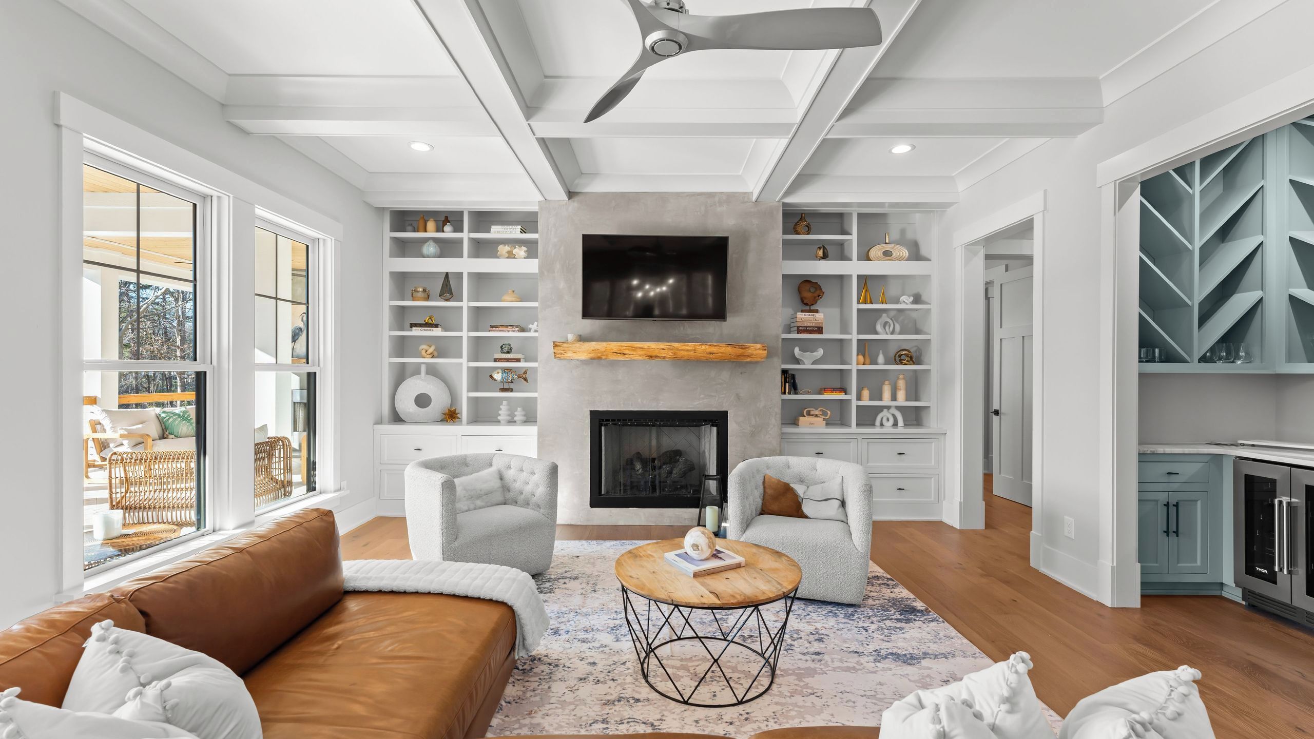 A modern living room with a fireplace, white shelving, and a dining area.