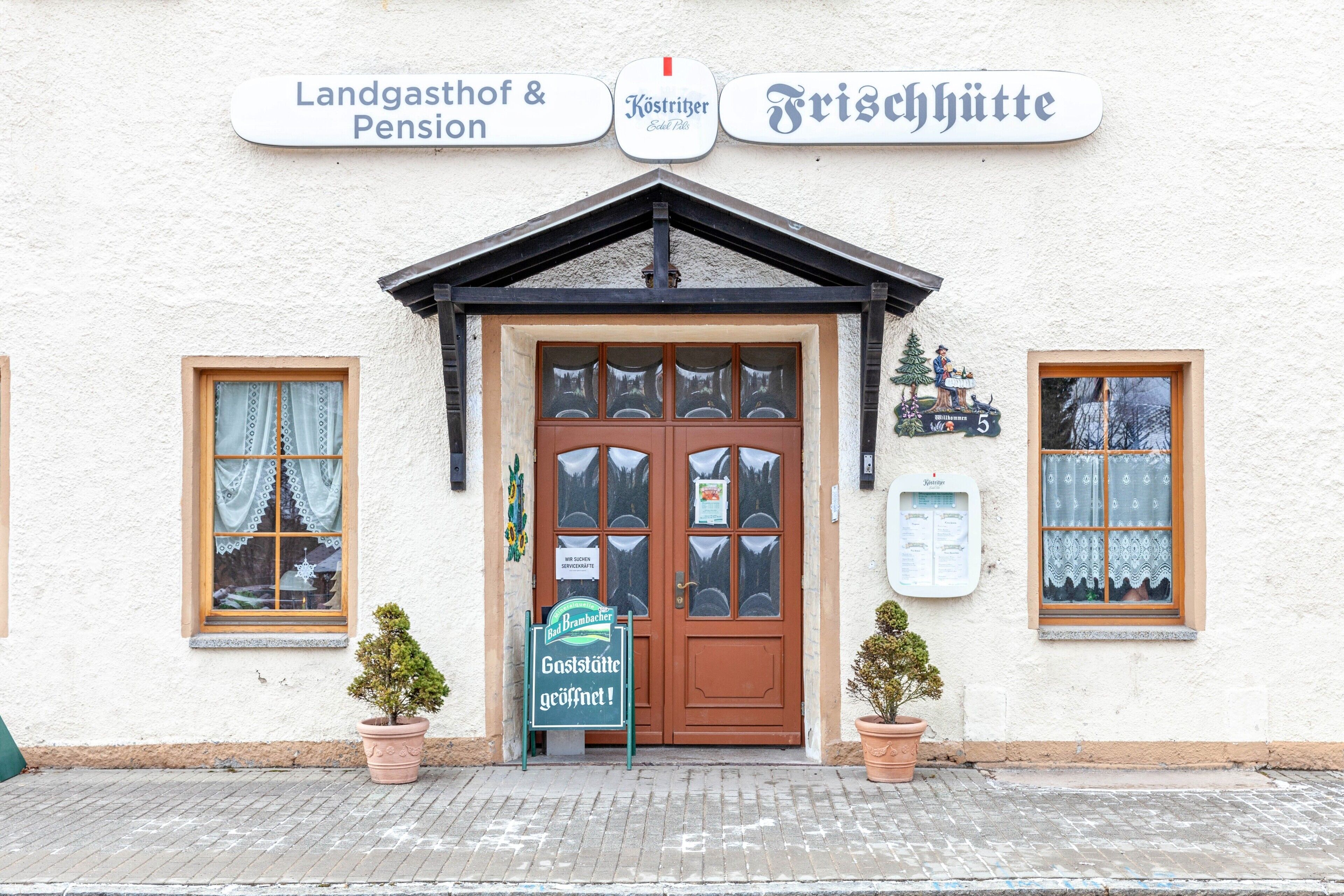 A building with a signboard indicating 'Landgasthof & Pension' and 'Frischhütte.'