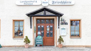 A building with a signboard indicating 'Landgasthof & Pension' and 'Frischhütte.'