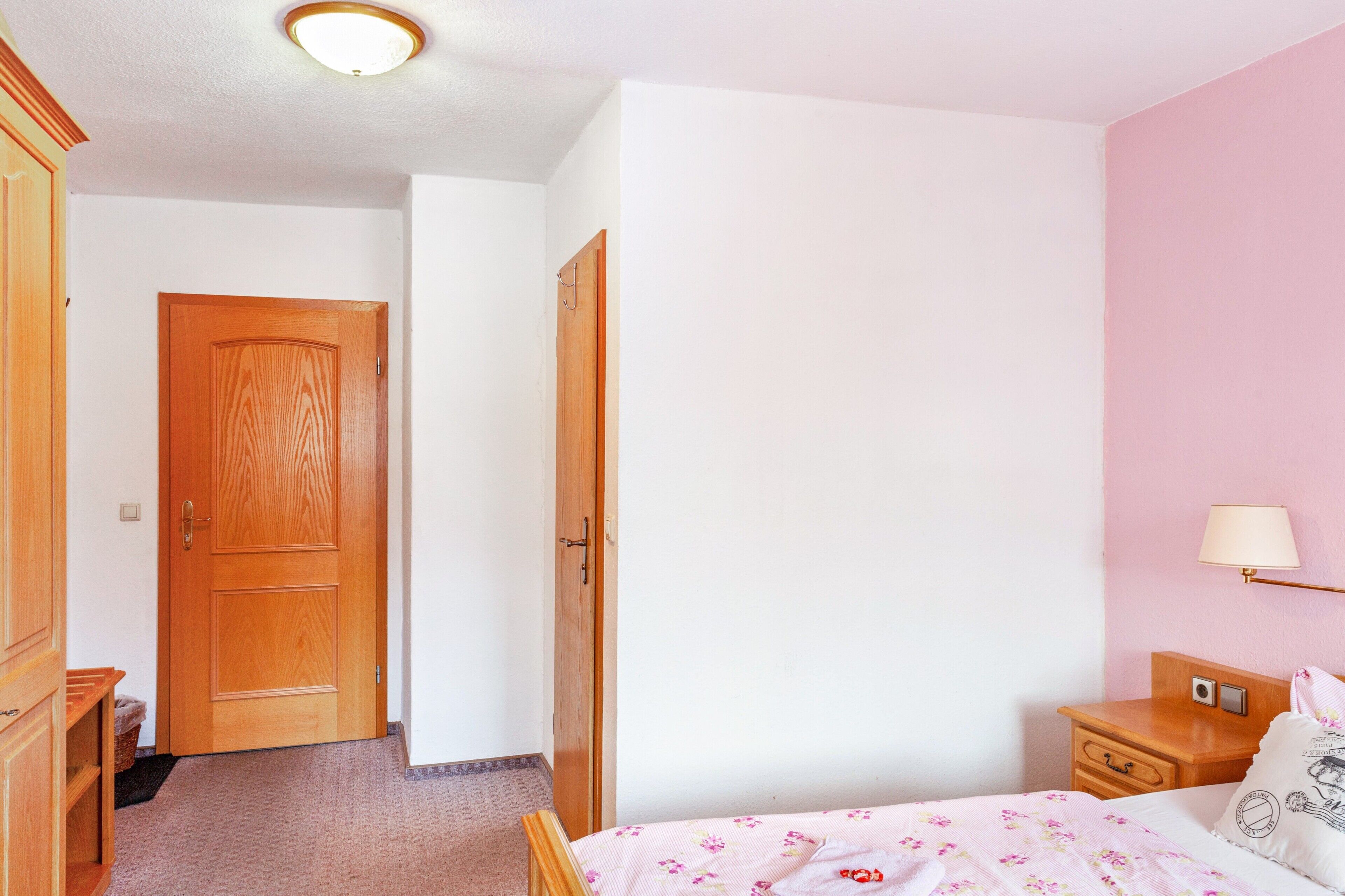 Ein Schlafzimmer mit einem Bett, einem Nachttisch, einer Lampe und einem Holzschrank.