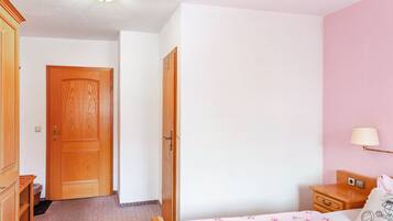 Ein Schlafzimmer mit einem Bett, einem Nachttisch, einer Lampe und einem Holzschrank.