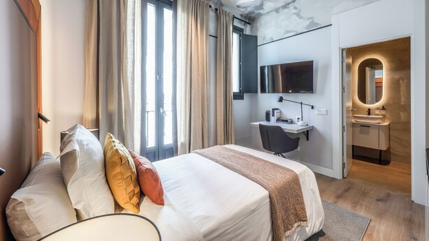 Une chambre d’hôtel moderne équipée d’un grand lit, d’un bureau, d’une télévision et d’une salle de bain.