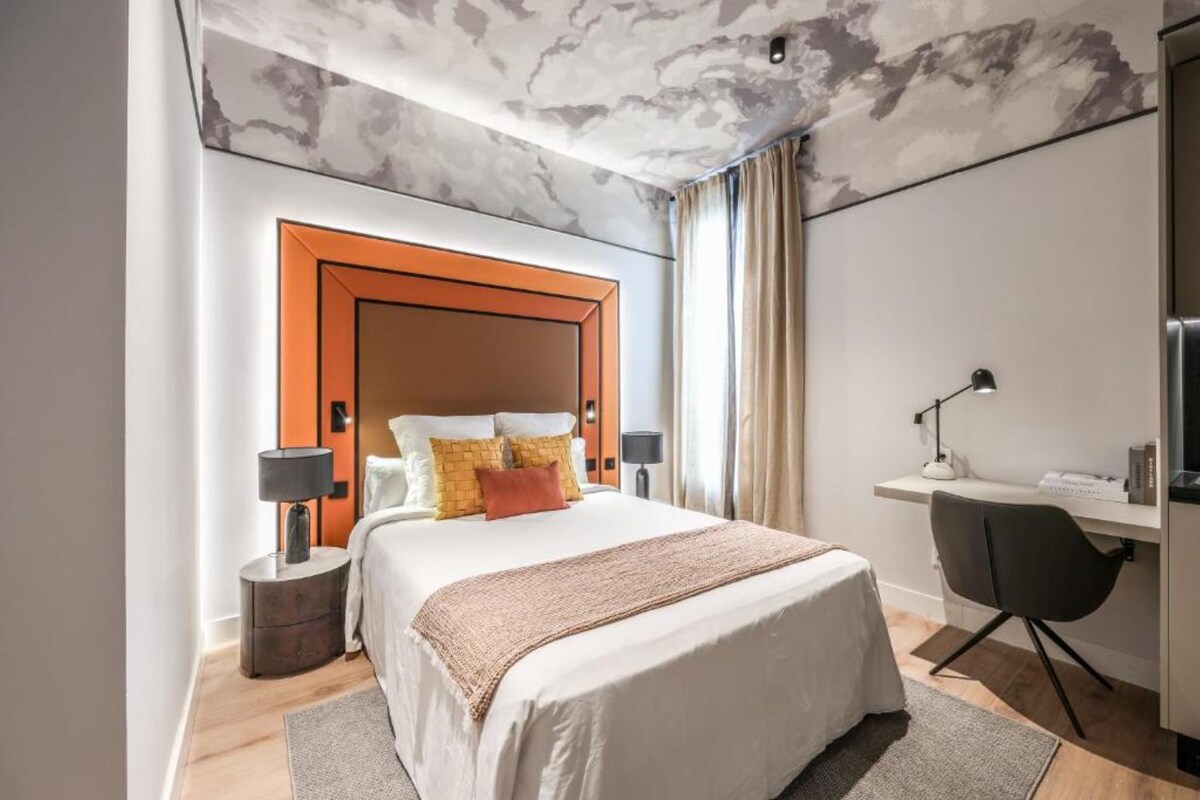 Een moderne hotelkamer met een groot bed, een bureau en een stoel.