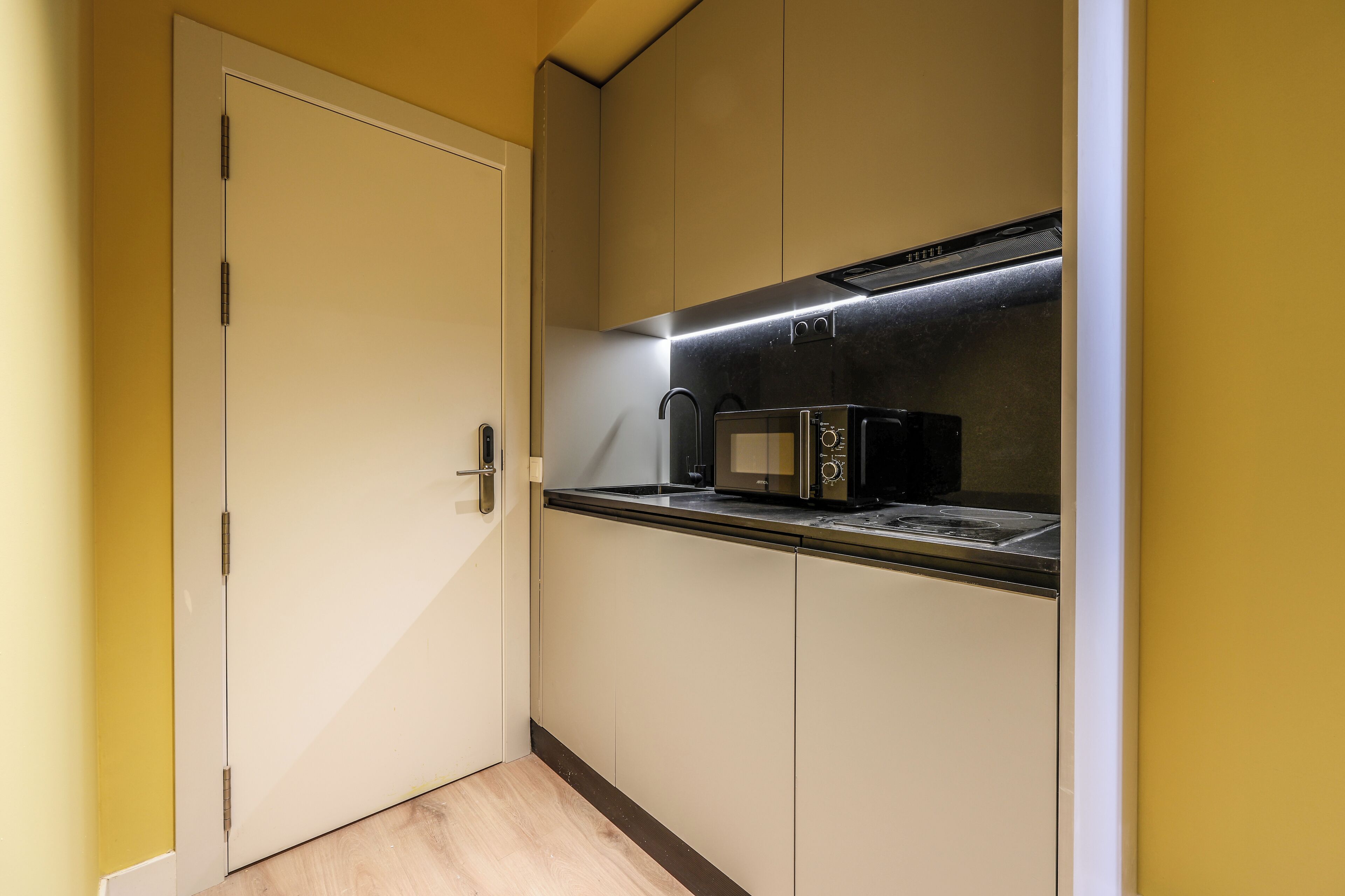 A compact kitchen with a microwave, oven, and built-in range hood.