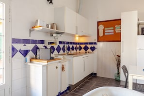Een keuken met witte kasten, een blauw-wit achterspatwand en een prikbord met bordjes.