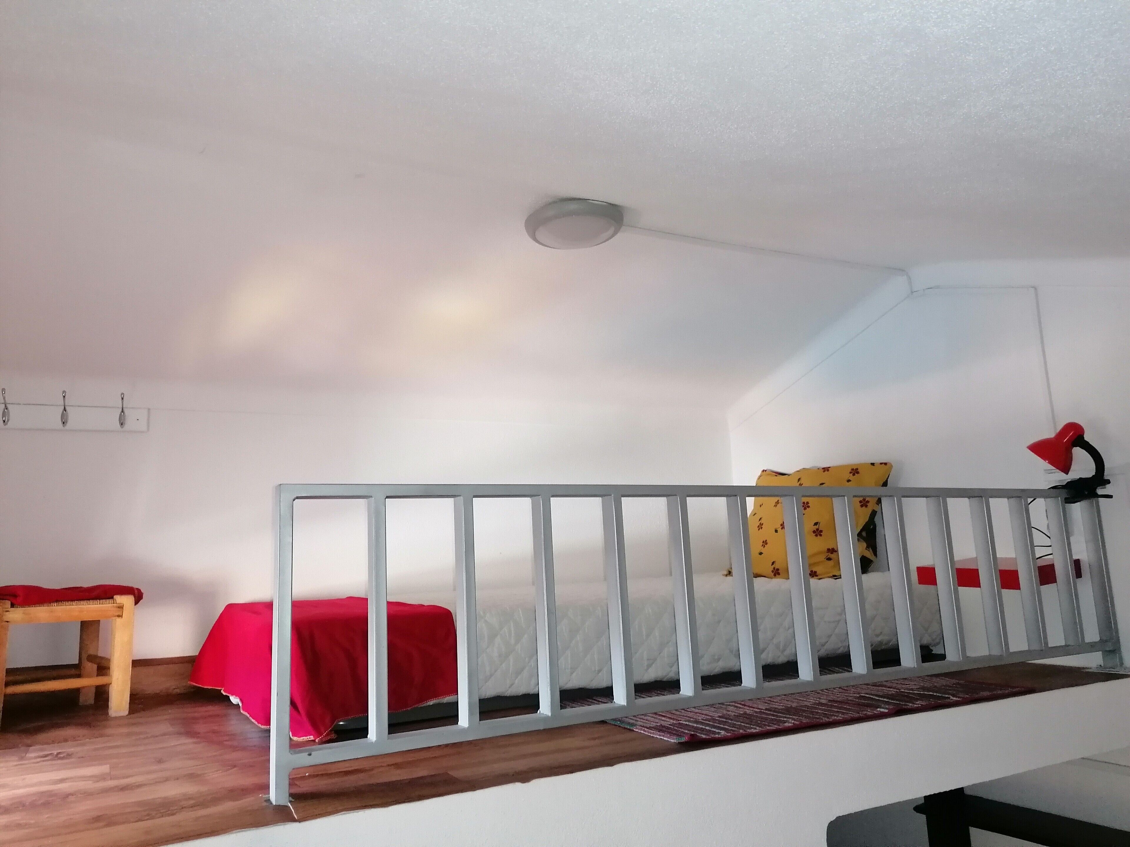 A room with a bed, a desk, a chair, a lamp, and a ceiling light.