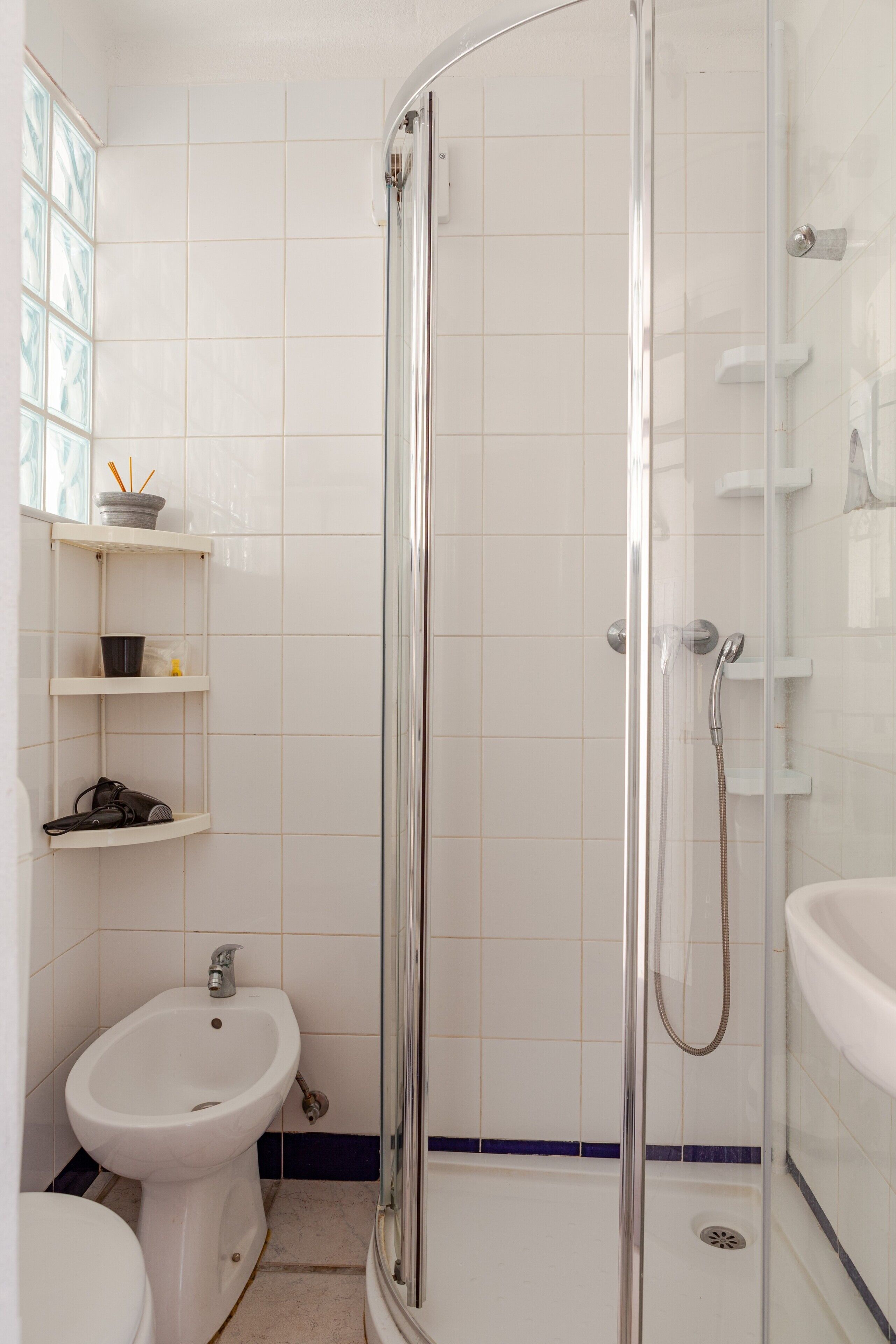 Un baño con ducha envuelta en vidrio, un bidé y un inodoro.