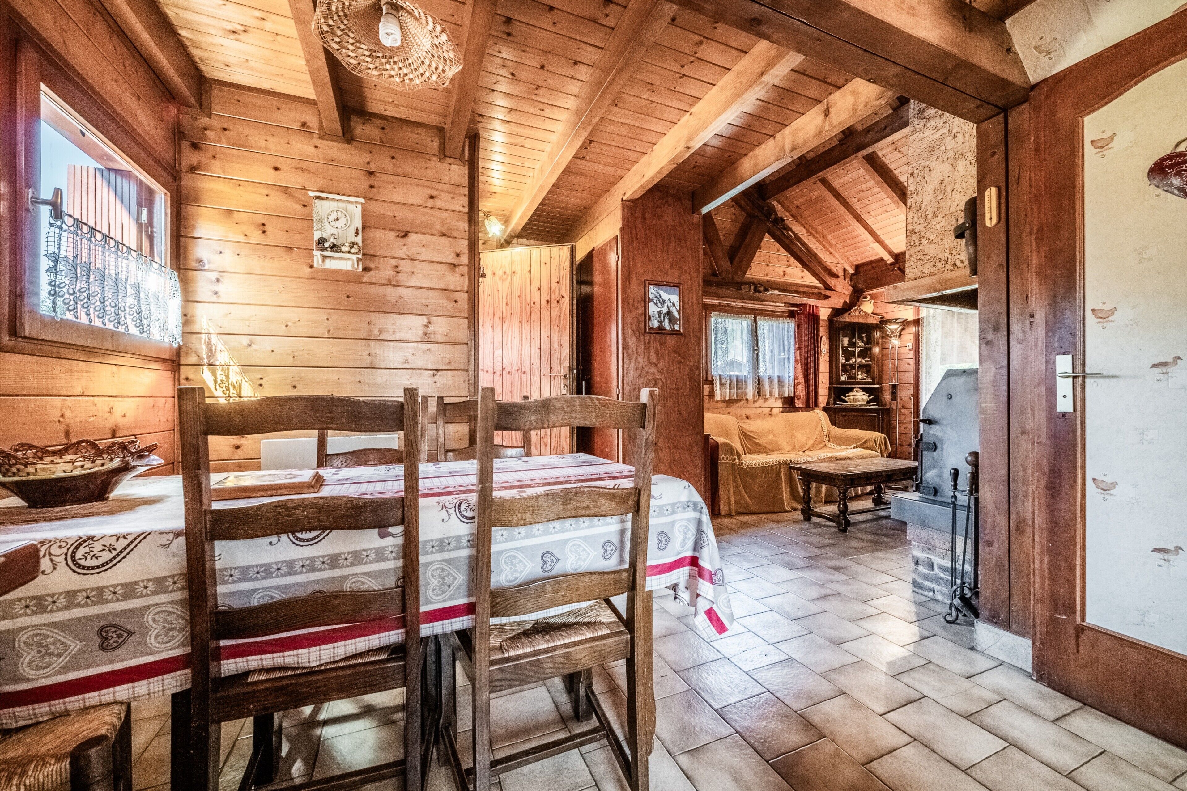 Un interior de madera con una mesa de comedor, sillas, una chimenea y una zona de cocina.