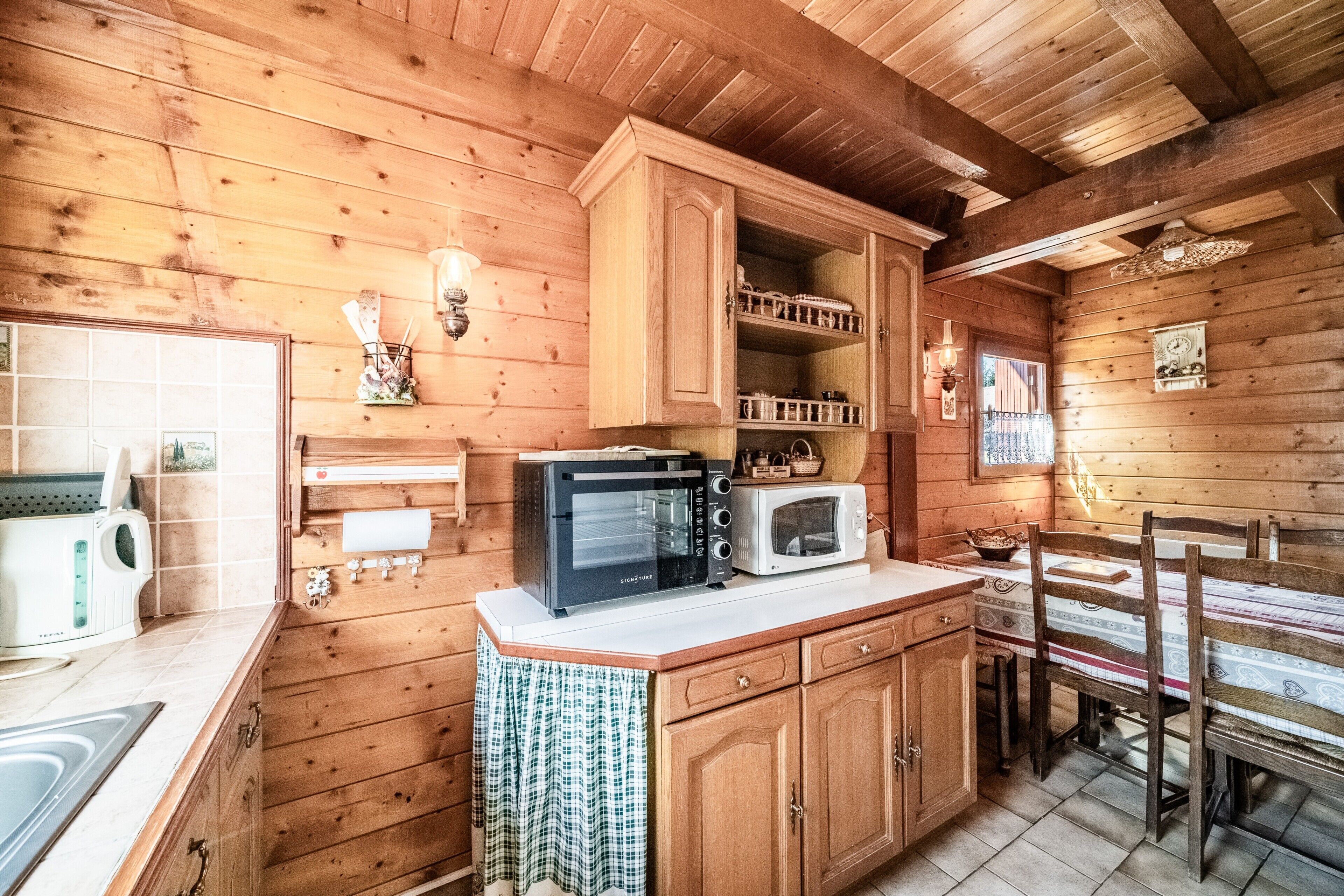 Ein Holzblockhaus-Innenraum mit Küchenbereich, einschließlich eines Toasters, einer Mikrowelle und Holzschränken.