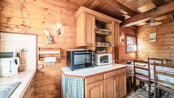 A wooden cabin interior with a kitchen area featuring a toaster, a microwave, and wooden cabinets.