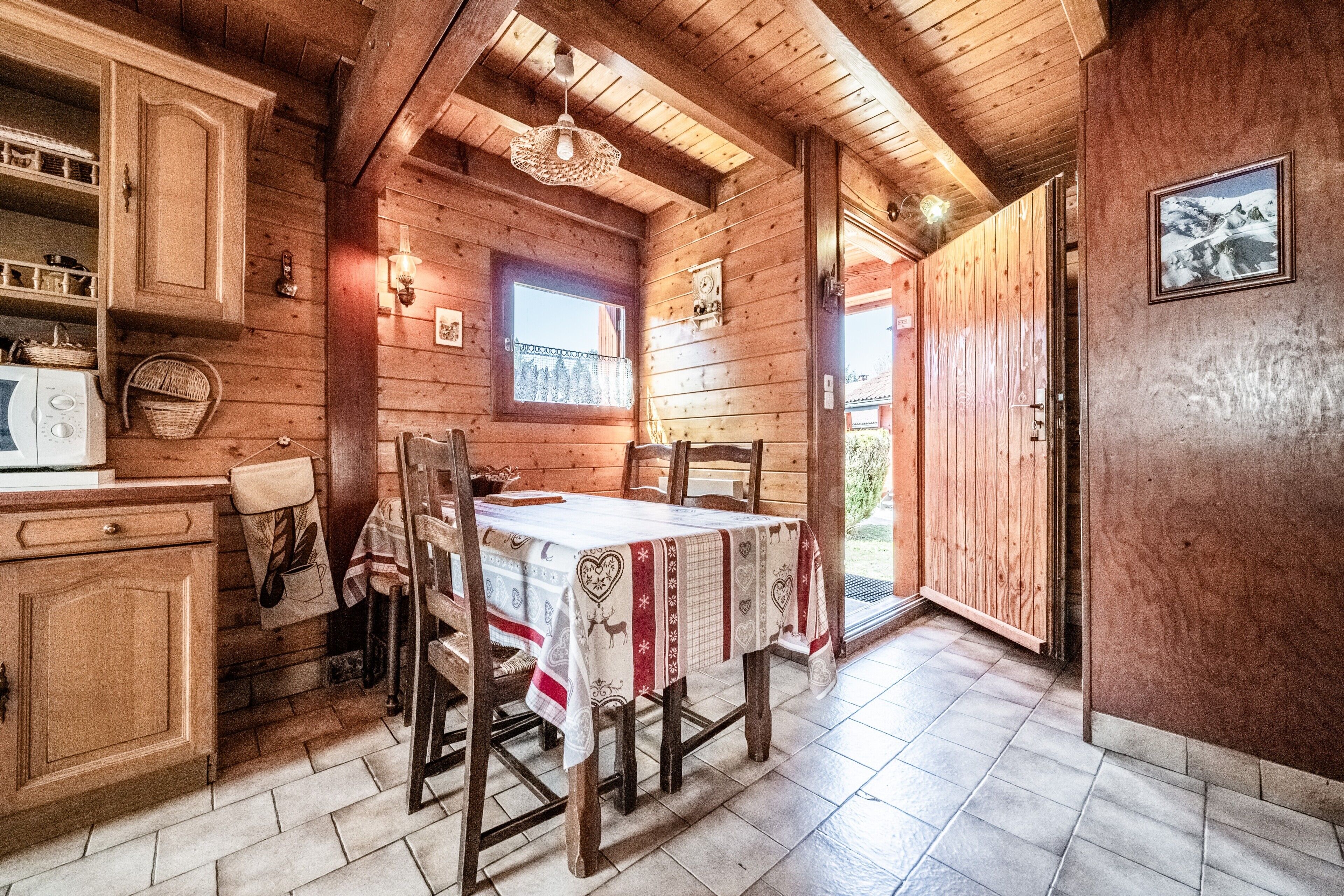 Un interior de madera con una mesa de comedor, sillas, una ventana y una puerta que da al exterior.