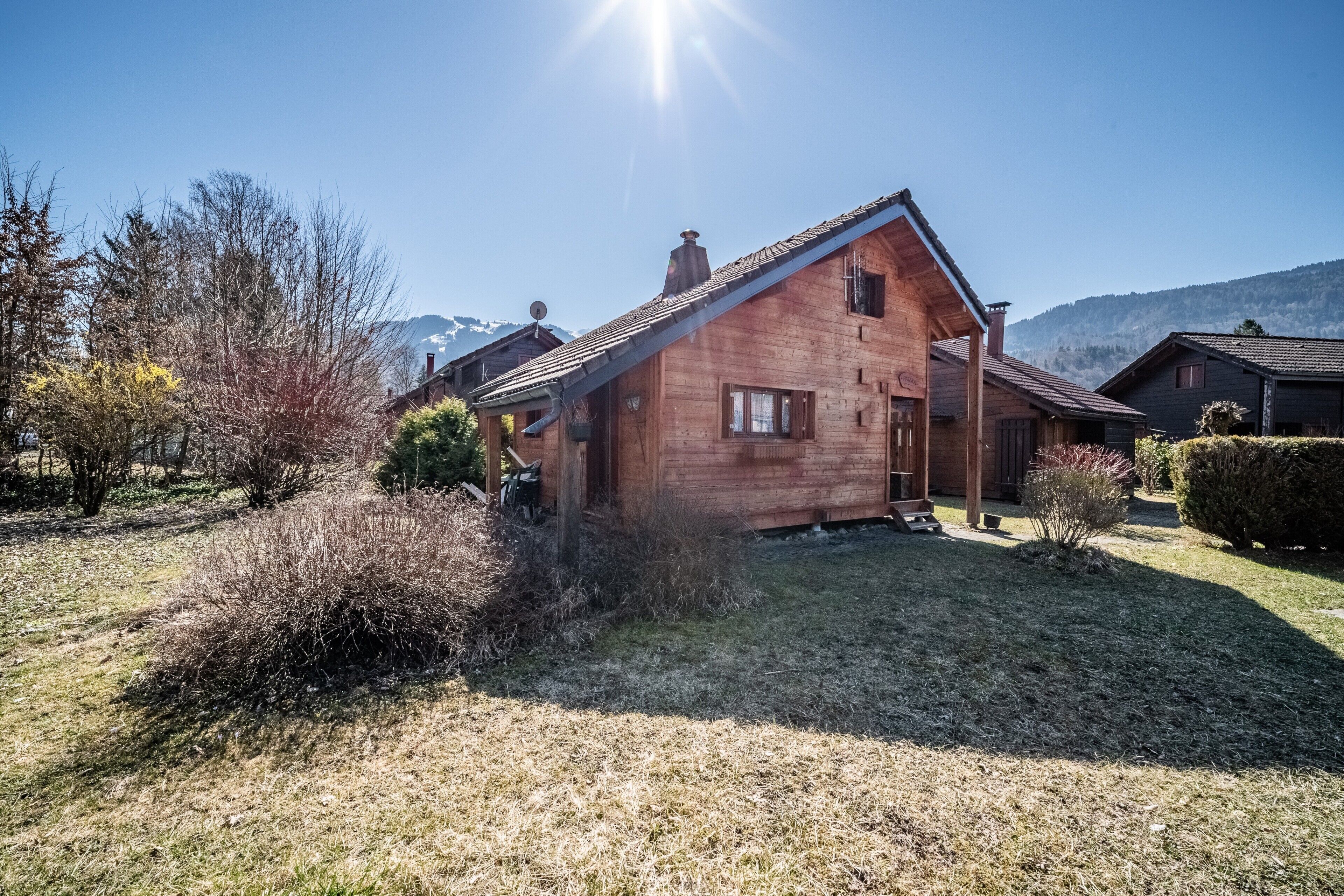Une maison en bois avec un toit en pente, une cheminée et un petit porche.