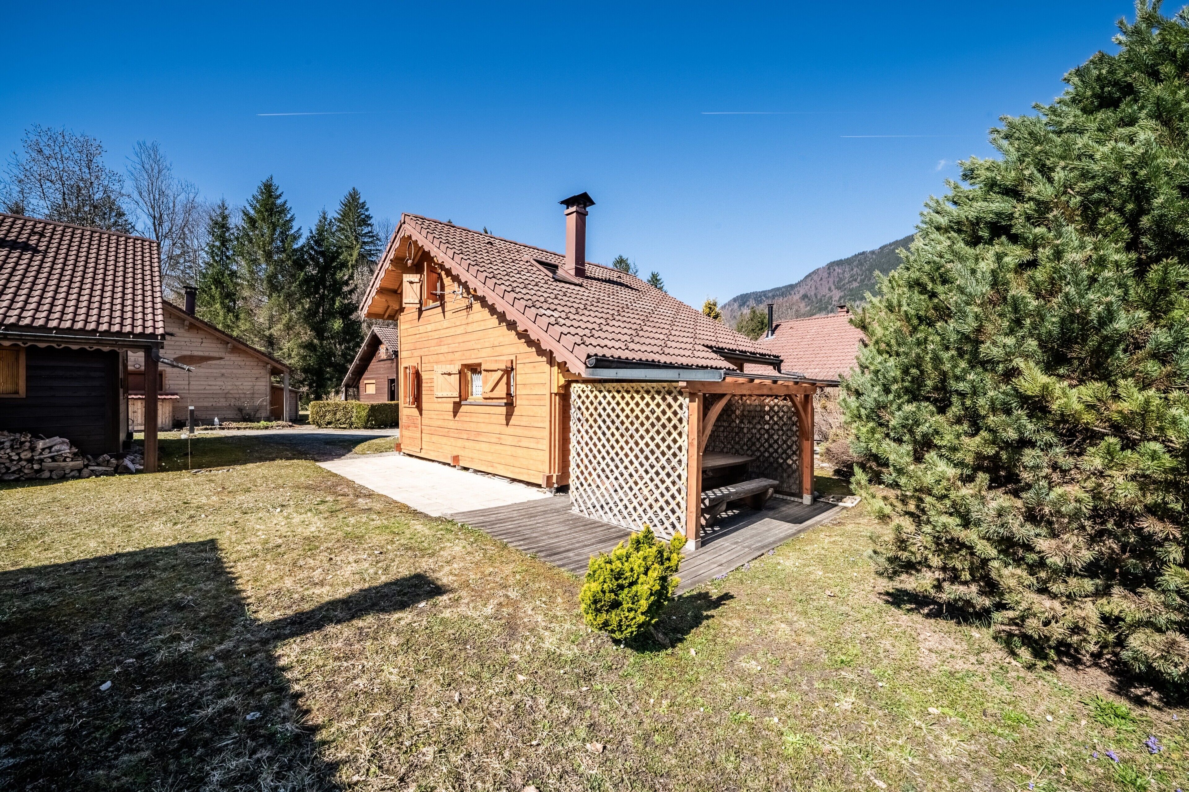 Una baita di legno con tetto spiovente, un patio in legno e un portico con grigliato.