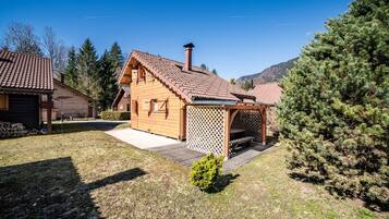 Una baita di legno con tetto spiovente, un patio in legno e un portico con grigliato.