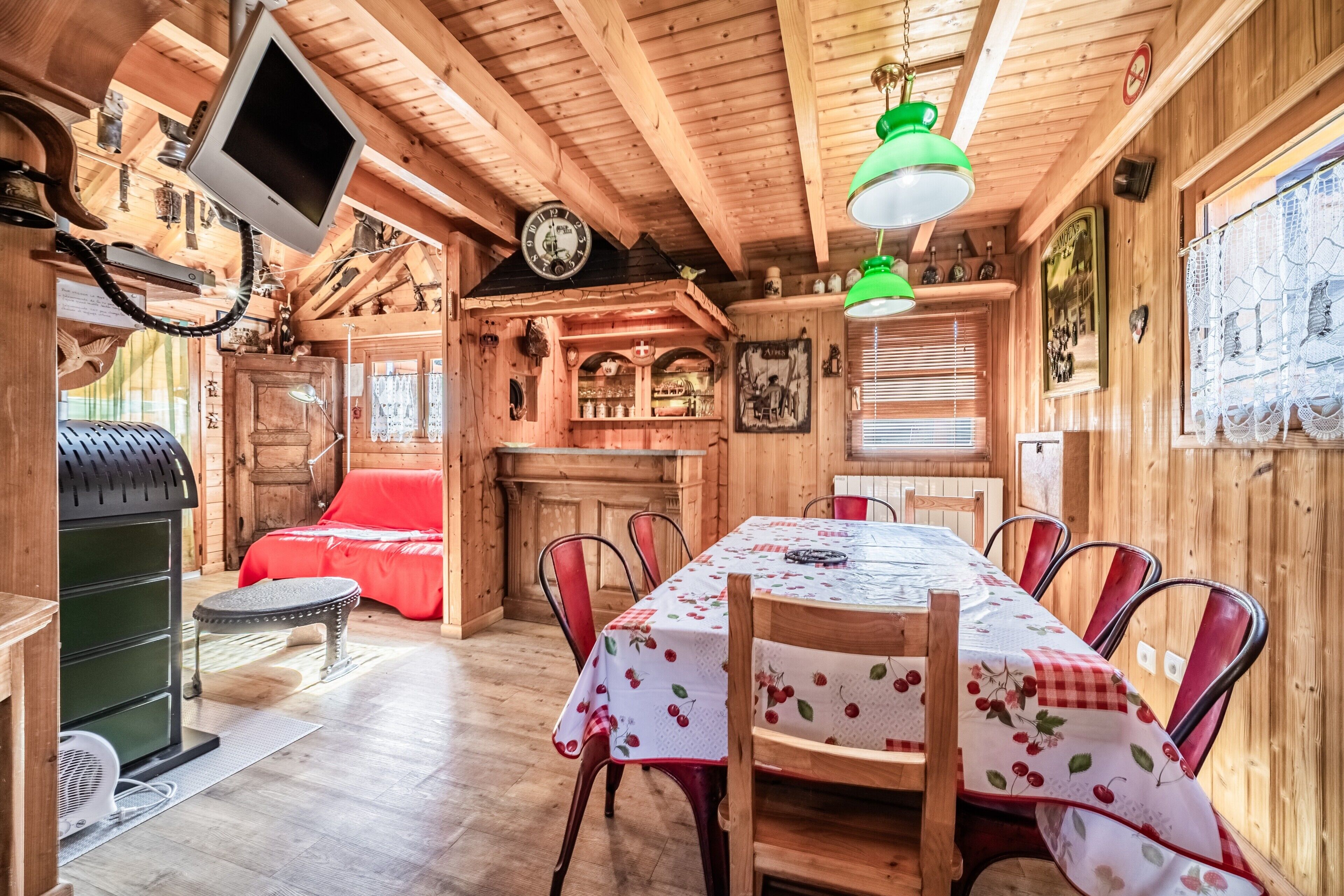Un interno in legno con un tavolo da pranzo, sedie, un divano rosso, una televisione e un orologio.