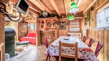 Un interno in legno con un tavolo da pranzo, sedie, un divano rosso, una televisione e un orologio.