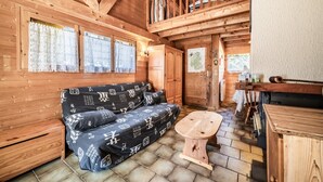 Et interiør af en træhytte med sofa, et lille træbord og en hems.