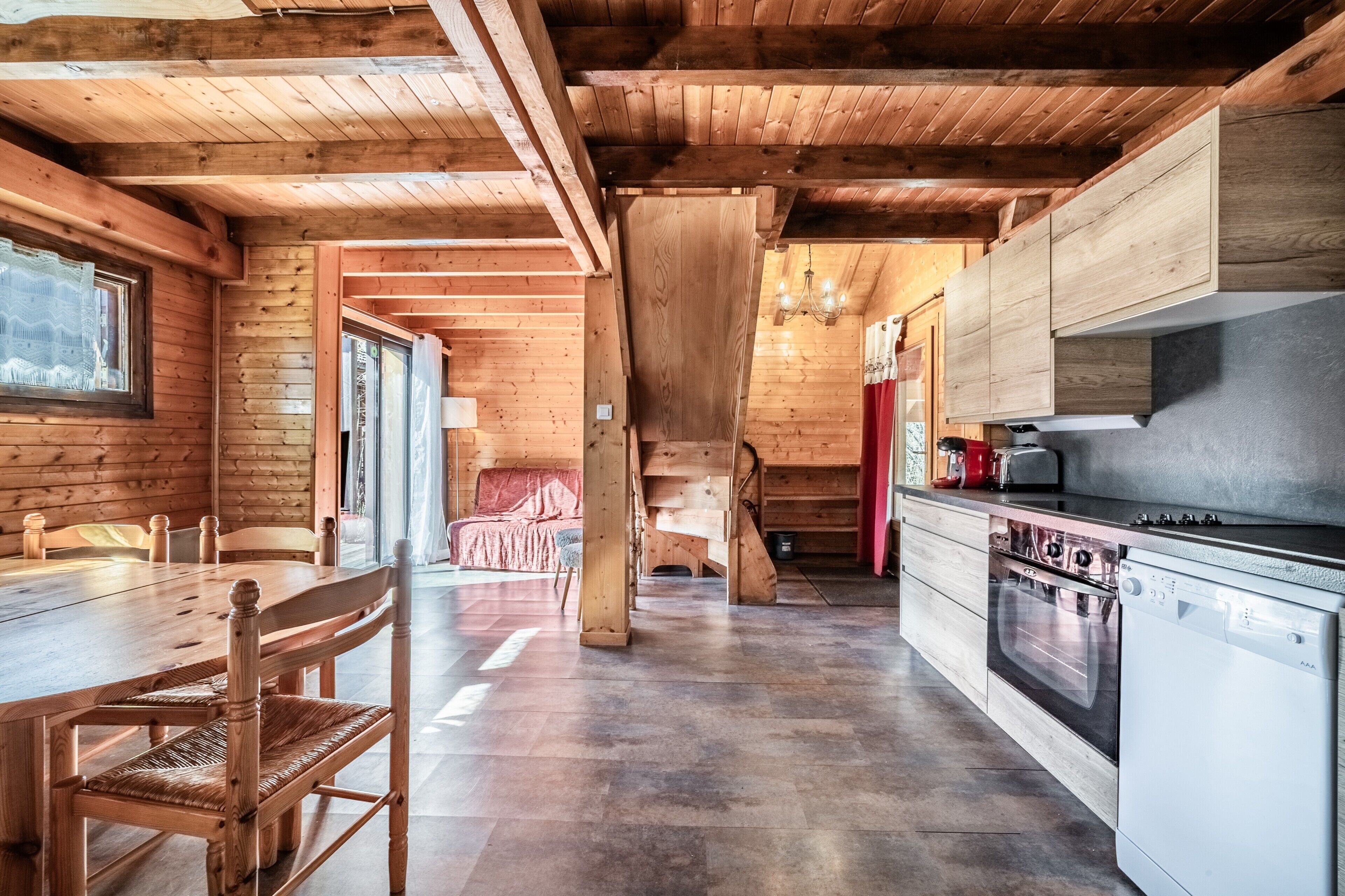 Un interior de madera con una mesa de comedor, sillas, una cocina equipada y una escalera.