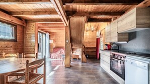 Un interior de madera con una mesa de comedor, sillas, una cocina equipada y una escalera.