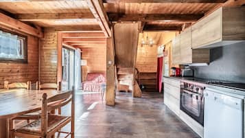 Un interior de madera con una mesa de comedor, sillas, una cocina equipada y una escalera.