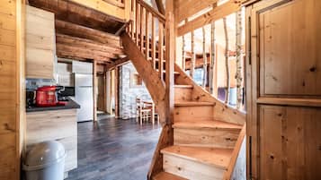 Una escalera de madera que lleva a un entrepiso con cocina y comedor.