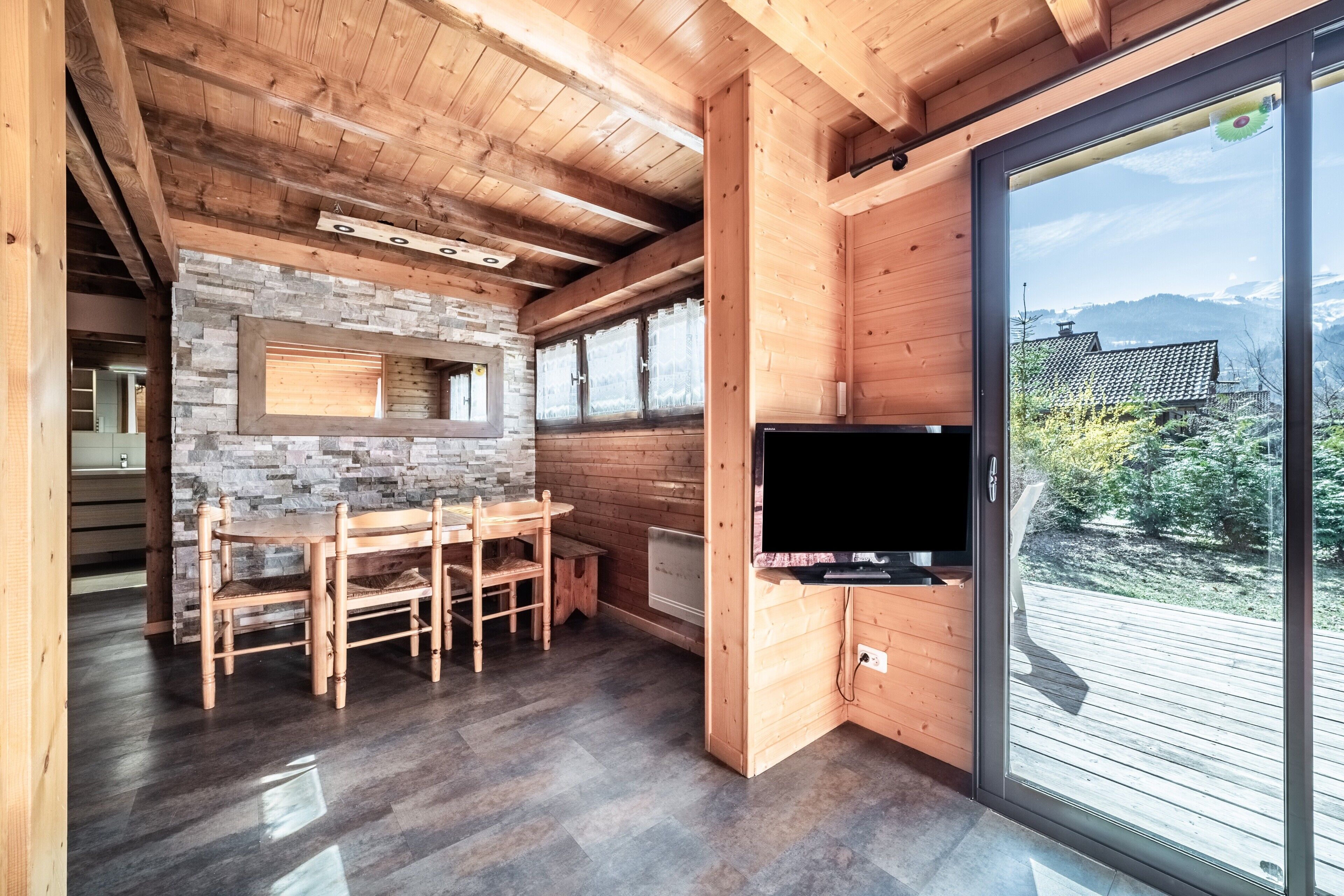Un interior de madera con una pared de piedra, una zona de comedor y un televisor.