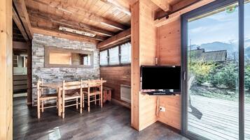 Un interior de madera con una pared de piedra, una zona de comedor y un televisor.