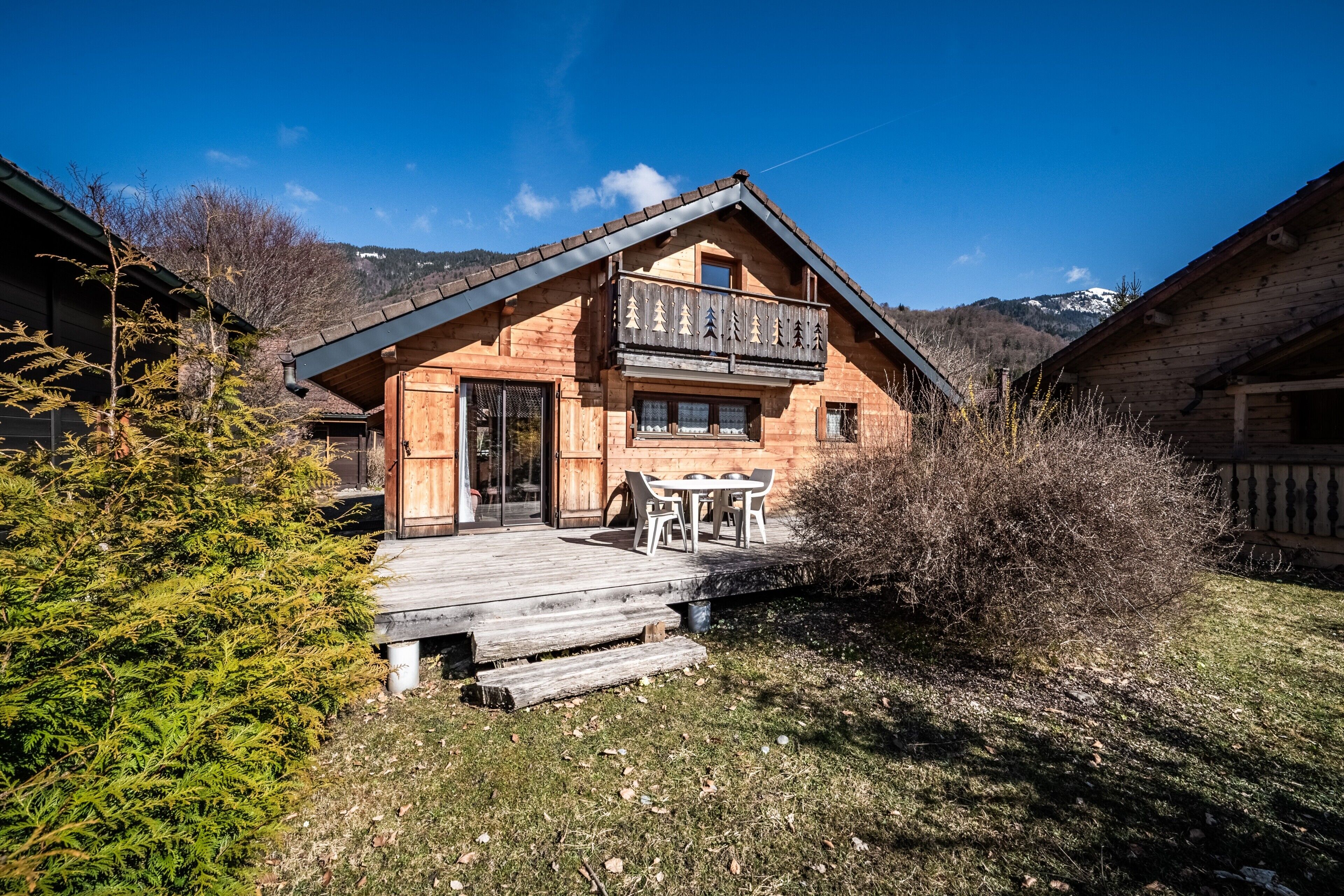 Een houten chalet met balkon, houten terras en een berg op de achtergrond.