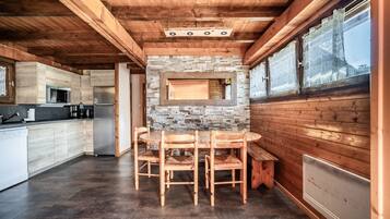 A wooden interior with a kitchen, dining table, and chairs.