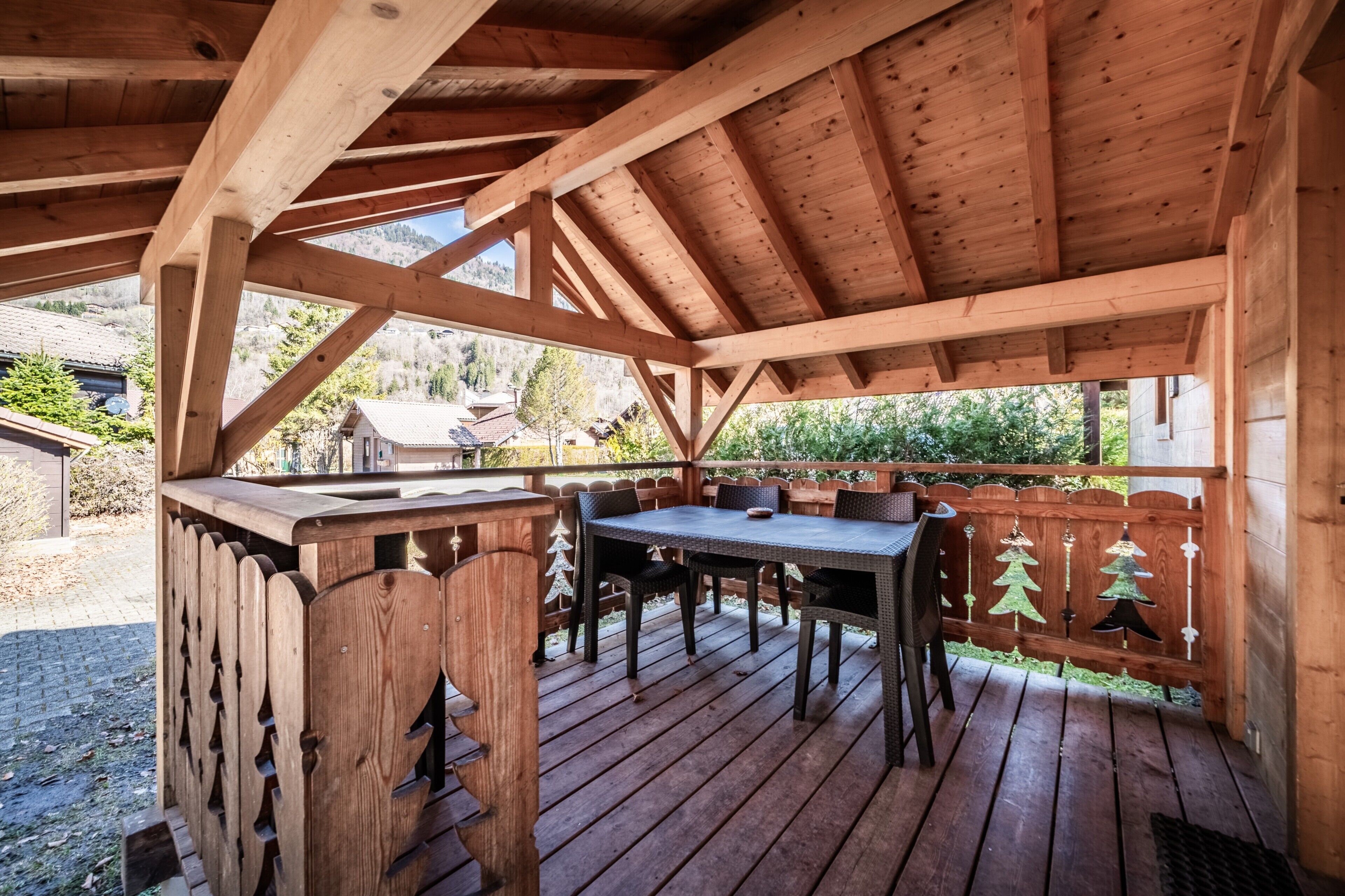 Une terrasse en bois avec une table et des chaises, entourée d’une clôture en bois décorée pour Noël.