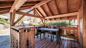 Une terrasse en bois avec une table et des chaises, entourée d’une clôture en bois décorée pour Noël.