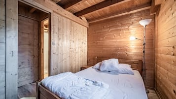 Un dormitorio de cabaña de madera con cama, lámpara de noche y armario de madera.