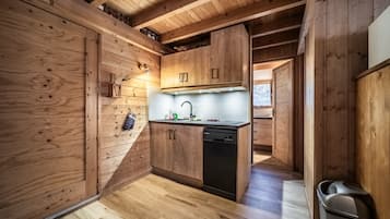 Un interior de madera con área de cocina, que incluye armarios, un lavamanos y un lavavajillas.