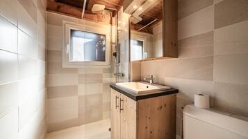 Een moderne badkamer met een houten wastafel, een raam en een douche.