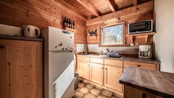 Cocina de cabaña de madera con refrigerador, microondas y armarios de madera.